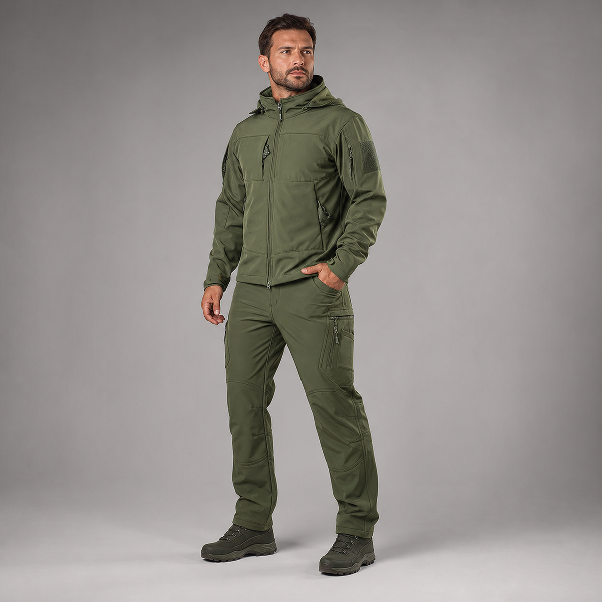 Man wearing green softshell jacket and utility trousers, full-body three-quarter studio view